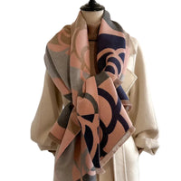 Mannequin wearing a beige coat with a patterned scarf against a plain background