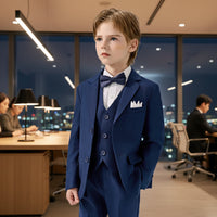 Young boy wearing a formal navy blue suit with a white shirt and bow tie on a office background