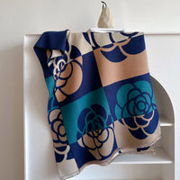 Scarf with floral pattern draped over a white shelf against a white background