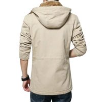 A man viewed from the back wearing a light beige hooded jacket with a brown faux-fur collar, paired with dark blue jeans against a plain light gray studio background.