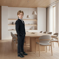 The  image of a young boy wearing a formal black suit with a white shirt and bow tie on a plain background.