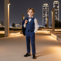 The image of a young boy in a formal blue suit with a bow tie on a plain background