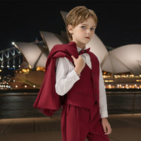 Child wearing a red vest over a white shirt on a plain background
