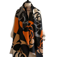 Mannequin wearing a patterned scarf with orange, black, and beige colors on a plain background.