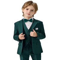 Young boy wearing a formal green suit with a white shirt and bow tie on a light gray background